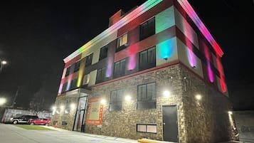 Un edificio de varios pisos con fachada de piedra e iluminación de colores.