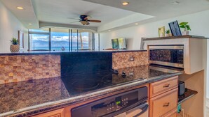A modern kitchen with a large island, a built-in oven, and a view of the ocean.