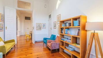 A room with wooden flooring, a bookshelf, a desk, and a chair.