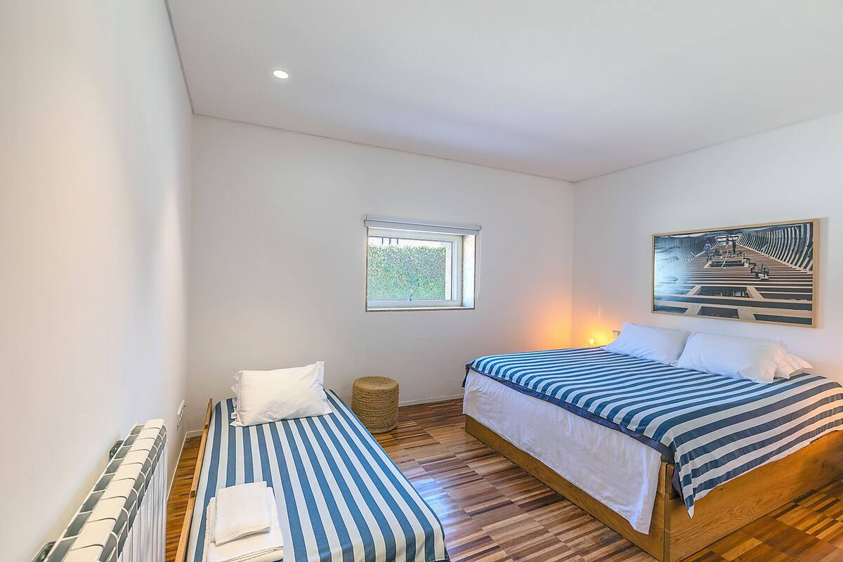 Une chambre avec deux lits, une fenêtre, un radiateur et un tableau.