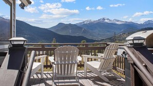 Una terraza con sillas Adirondack con vistas a un paisaje montañoso.