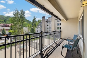 A balcony with a view of a residential area, a table with chairs, and a railing. - Vail/Lionshead 2-bedroom condo, walk to Ski Lifts (Vail)