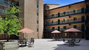 Une cour avec des espaces de repos en plein air et un immeuble à plusieurs étages doté de balcons.
