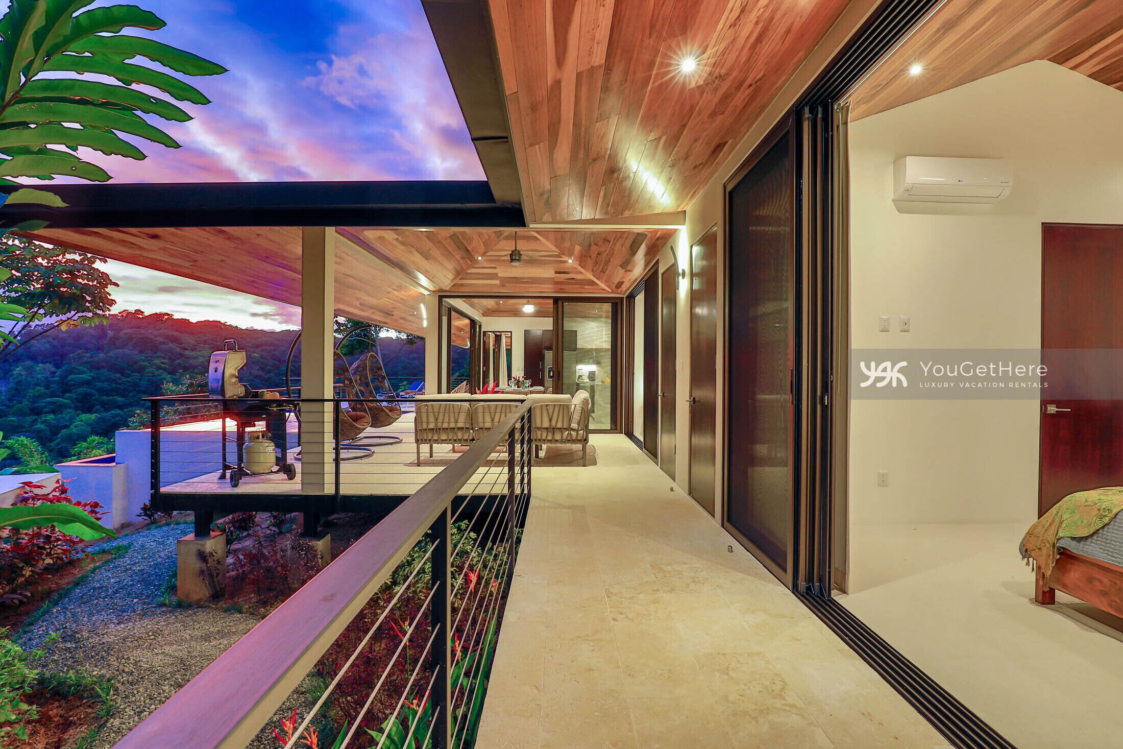 A modern villa with a balcony, a dining area, and a view of the mountains.