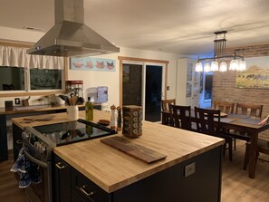 Een moderne keuken met een centraal eiland, een inbouwoven en een eethoek met houten stoelen en een tafel.