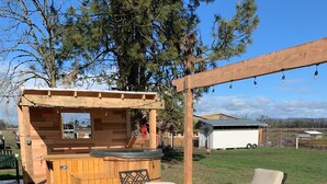 Eine Holzterrasse mit integriertem Grillbereich, einem Tisch mit Stühlen und einer Pergola mit Lichterketten.