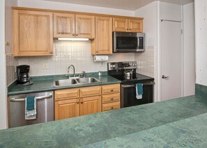 Kitchen area with a microwave, kettle, and stainless steel sink.
