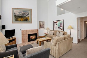 A living room with a fireplace, sofas, a television, and artwork on the walls.