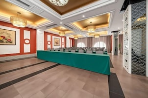 Un salón de conferencias con una larga mesa, varias sillas y un techo decorativo.