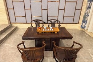 Una mesa de comedor con cuatro sillas, una bandeja de madera con objetos y una pared tradicional al fondo.