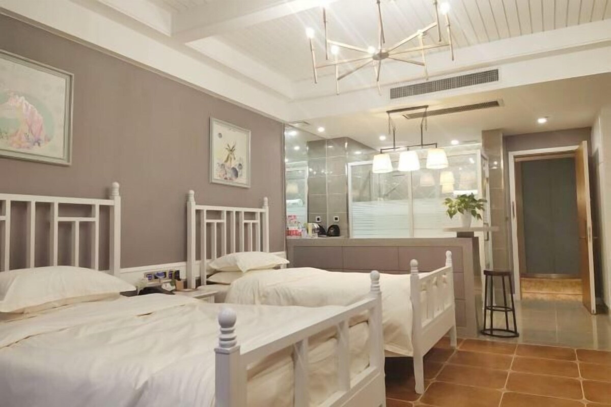A bedroom with two single beds, a vanity with a mirror, and a small stool.