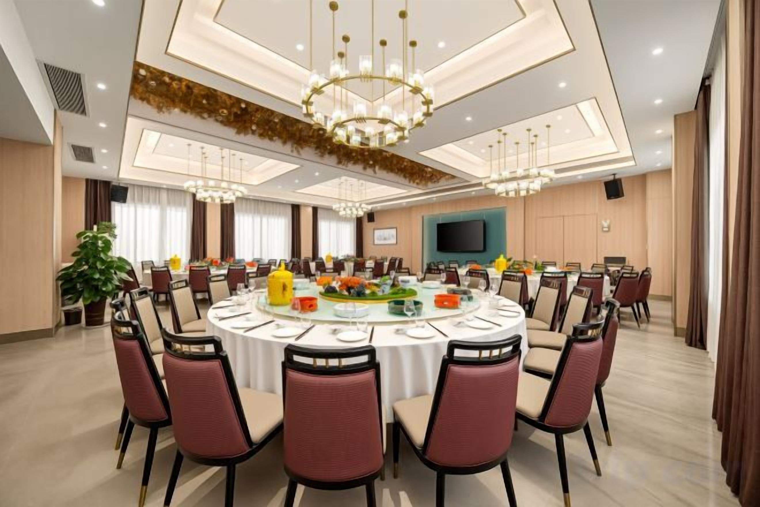 Une salle de conférence avec une table ronde, des chaises et un lustre.