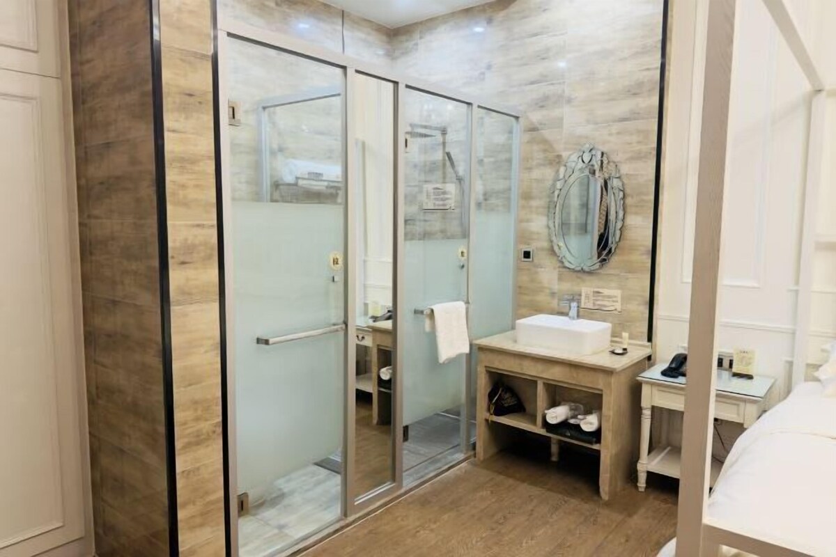 A modern bathroom with a glass shower enclosure, a vanity with a sink, and a mirror.