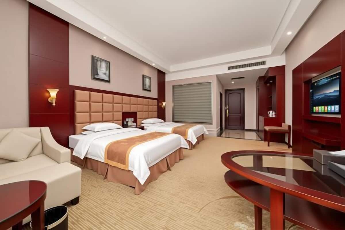 Une chambre d’hôtel avec deux lits, un canapé, une télévision et un bureau.