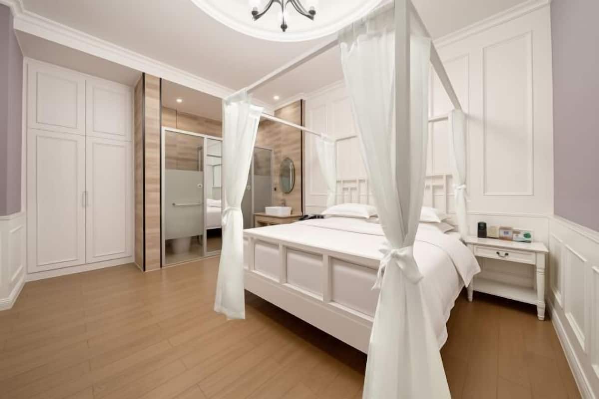 Une chambre à coucher avec un lit à baldaquin, une table de chevet, un miroir et une armoire.