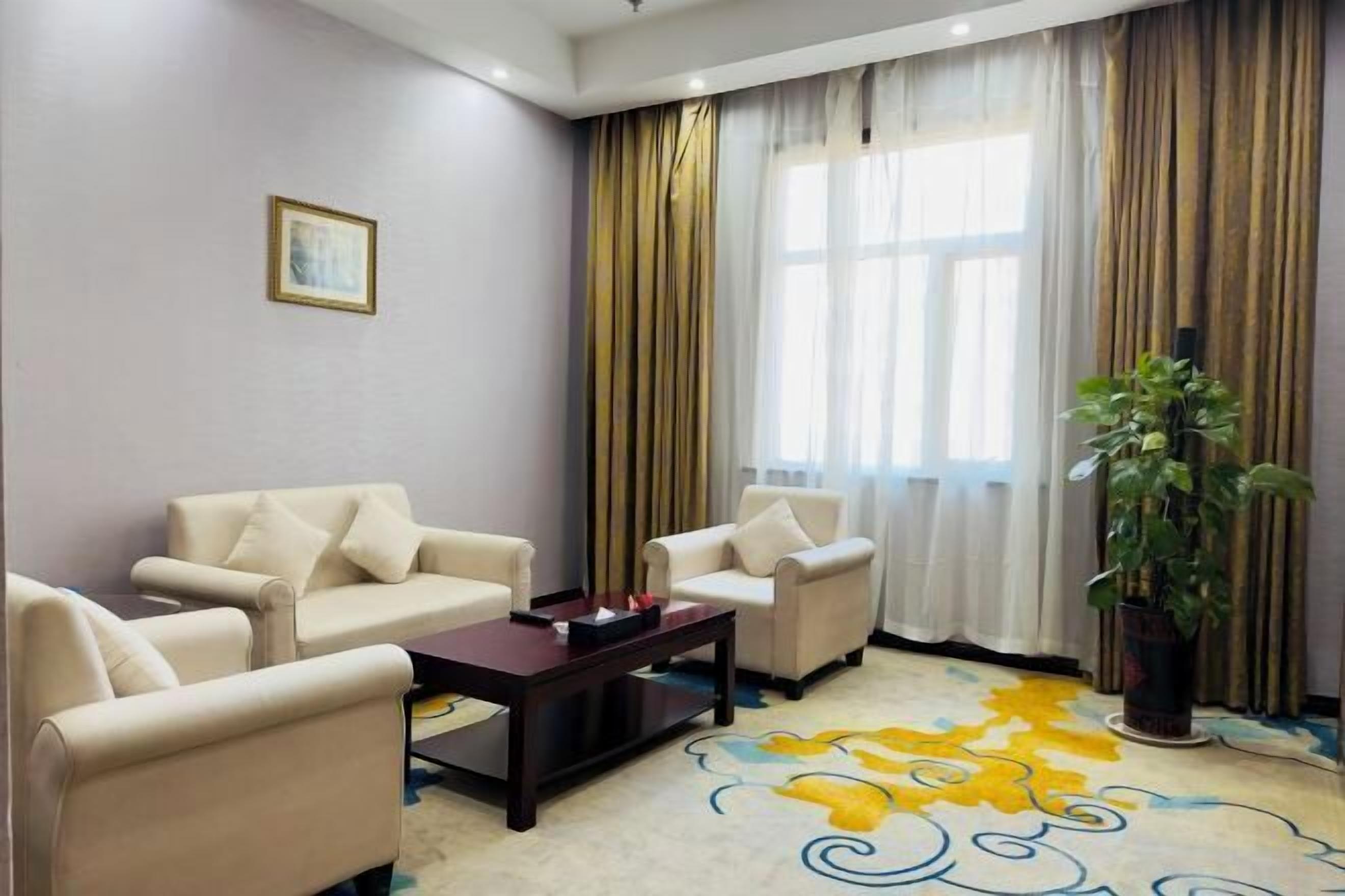A living room with beige sofas, a dark coffee table, and a colorful carpet.