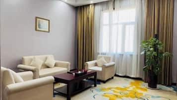A living room with beige sofas, a dark coffee table, and a colorful carpet.