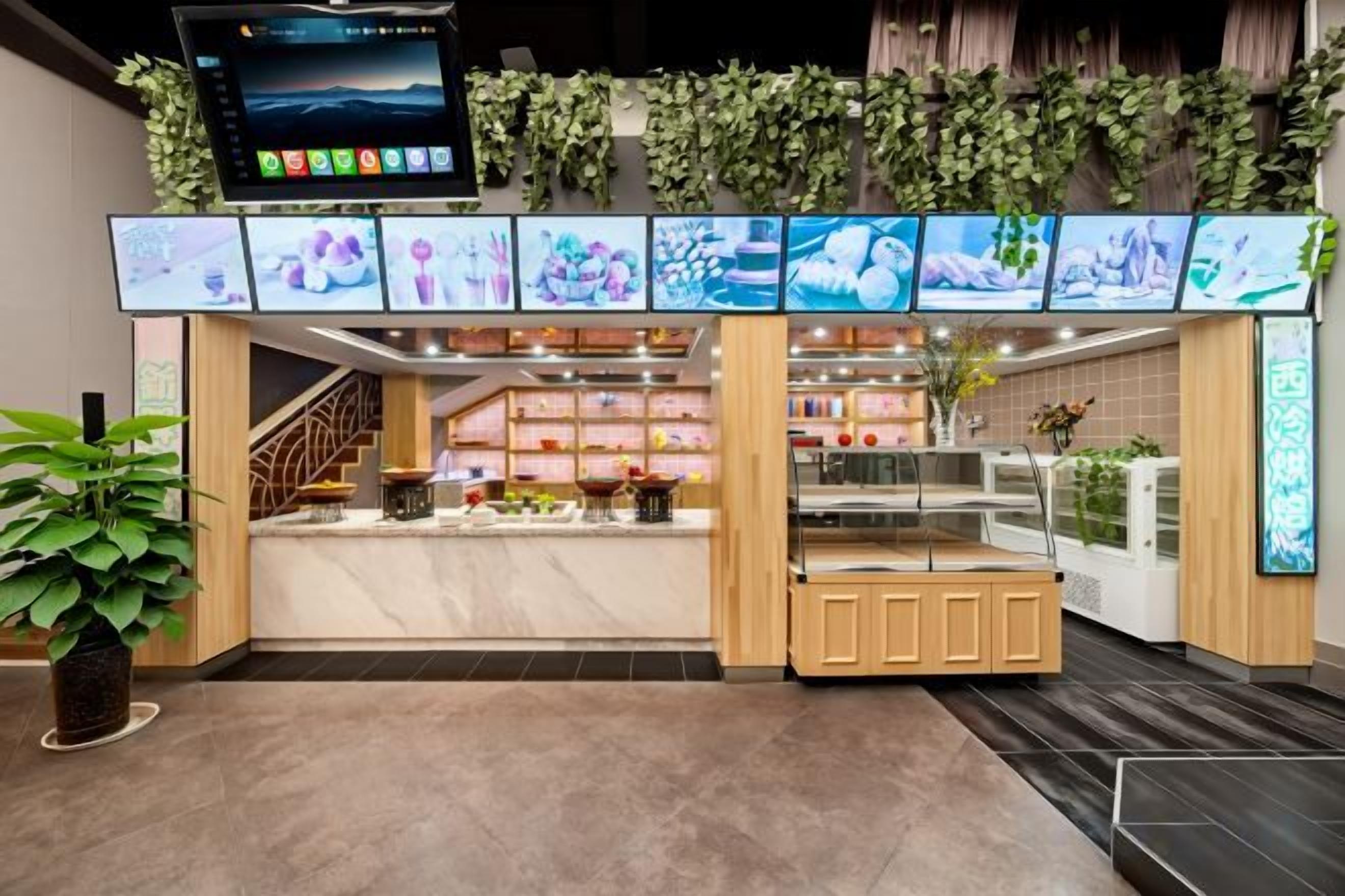 A modern kiosk with a digital menu display, a seating area, and a counter with a glass display case.