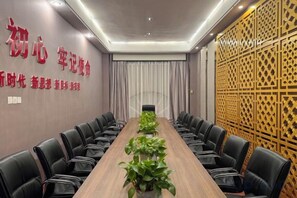 Une salle de conférence avec une longue table, des chaises noires et des plantes en pot.