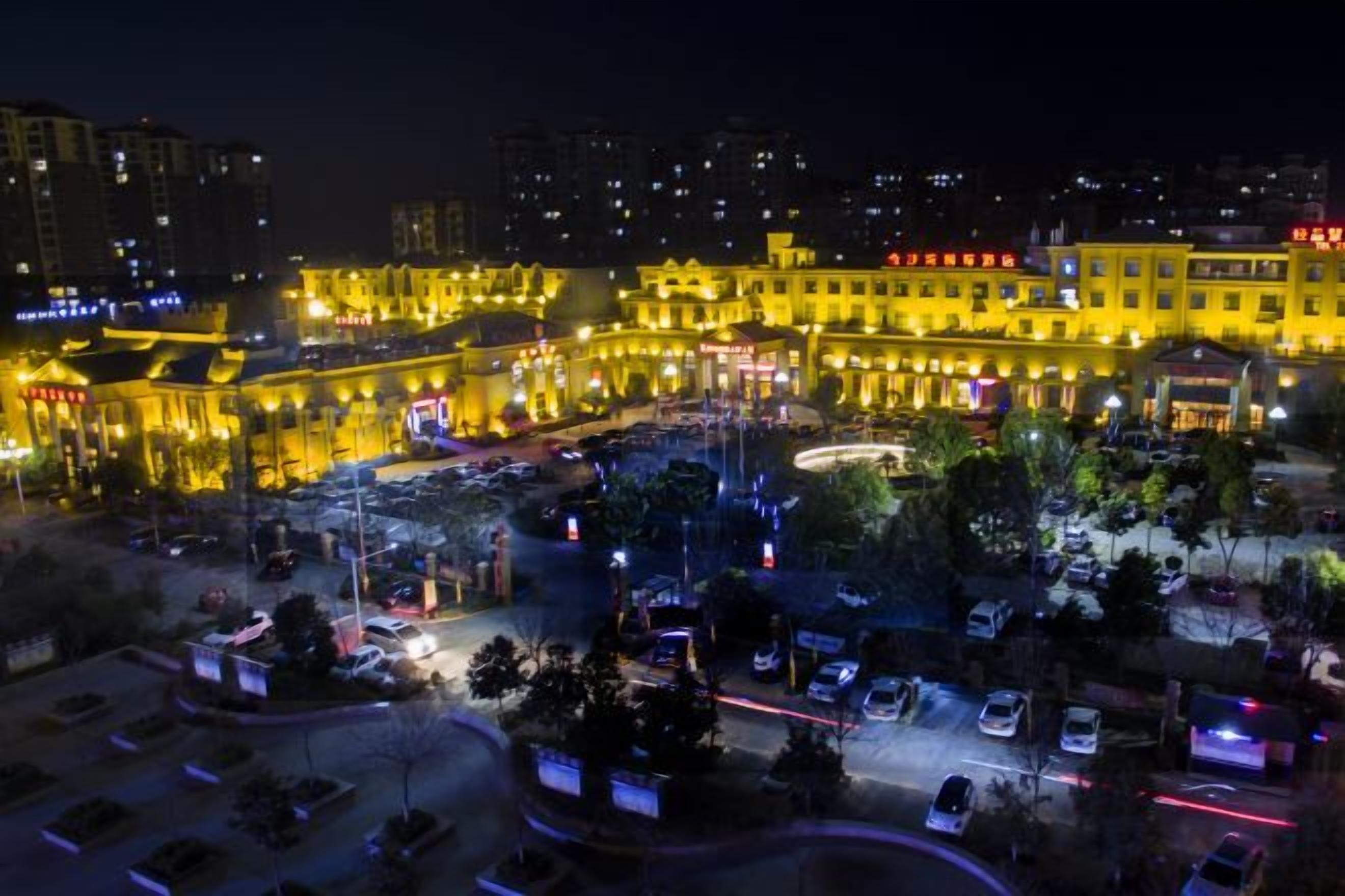 A hotel with multiple floors, a central courtyard, and a parking area.