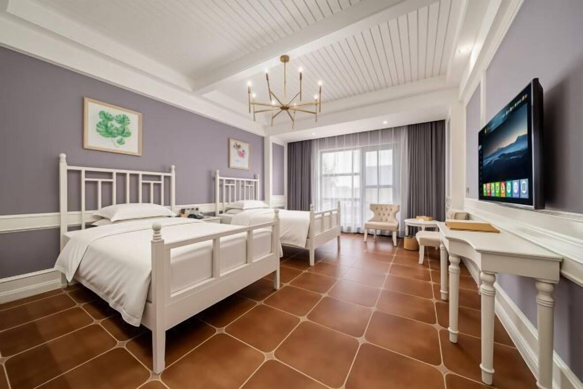 Une chambre d’hôtel avec deux lits, un bureau, une télévision et une grande fenêtre.