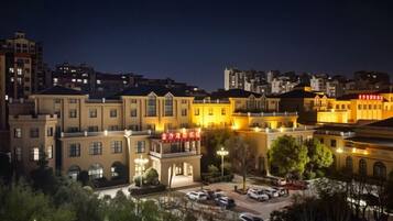 A hotel with multiple floors, a parking area, and a well-lit facade.