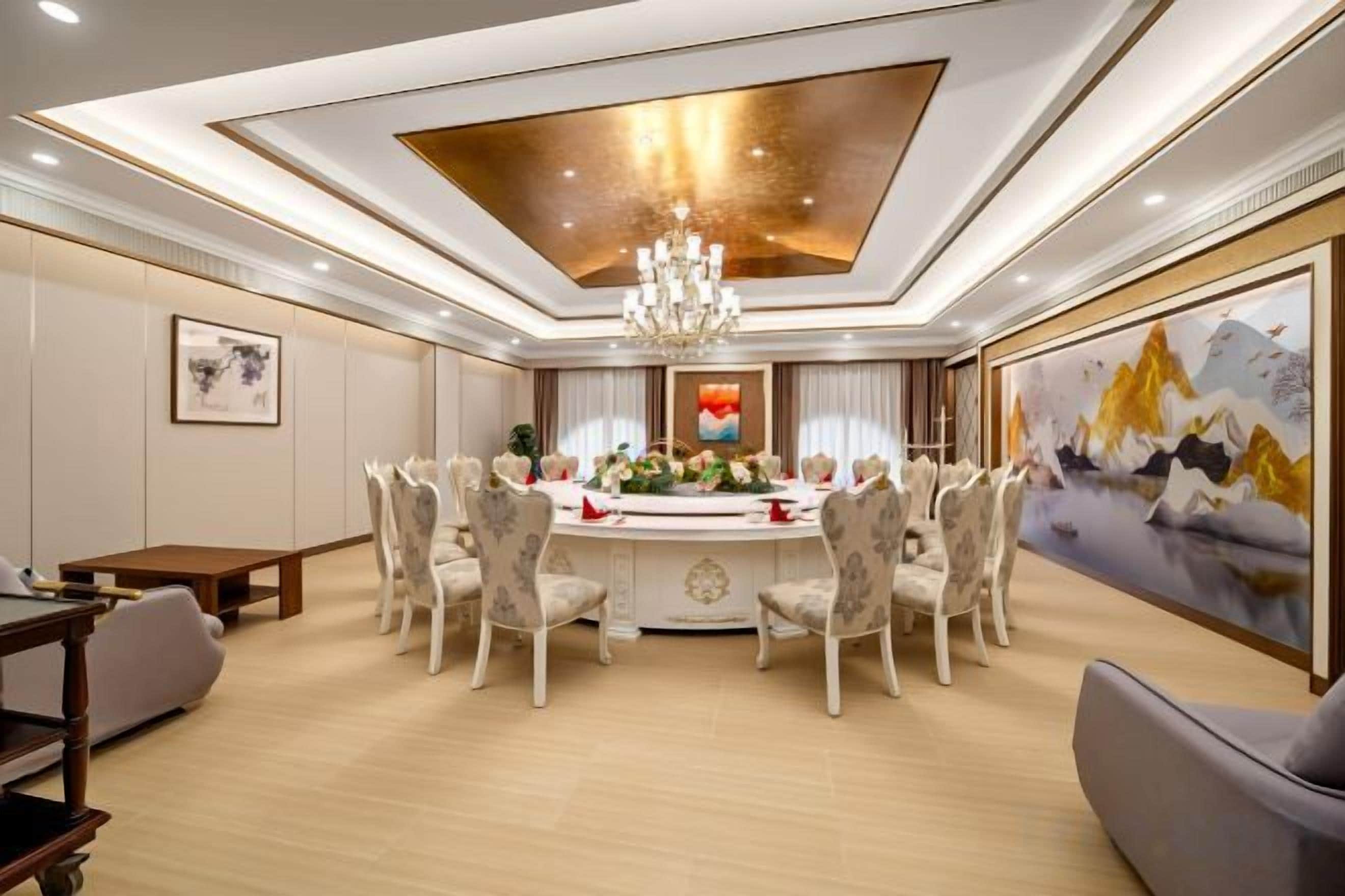 A dining area with a round table, chairs, and a chandelier.