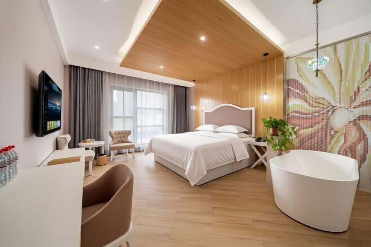 Une chambre d’hôtel moderne équipée d’un lit, d’un coin salon, d’une télévision et d’une grande fenêtre.
