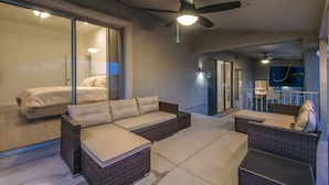 Un espace de vie extérieur moderne, comprenant un canapé, des fauteuils et un ventilateur de plafond.