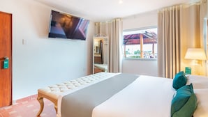 Una habitación de hotel con una cama, un televisor montado en la pared, una ventana con cortinas y una puerta con cerradura.