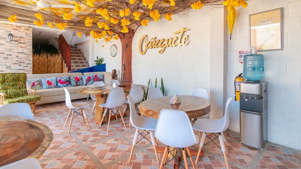 Un comedor con una mesa redonda, sillas blancas y un techo decorado con flores amarillas.