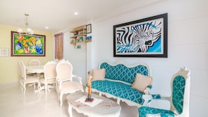 Una sala de estar con un sofá blanco, sillones a juego, una mesa de centro y un cuadro con temática de cebra en la pared.