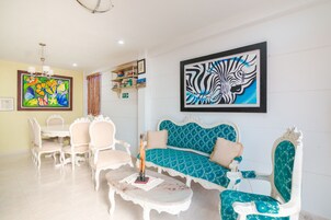Una sala de estar con un sofá blanco, sillones a juego, una mesa de centro y un cuadro con temática de cebra en la pared.
