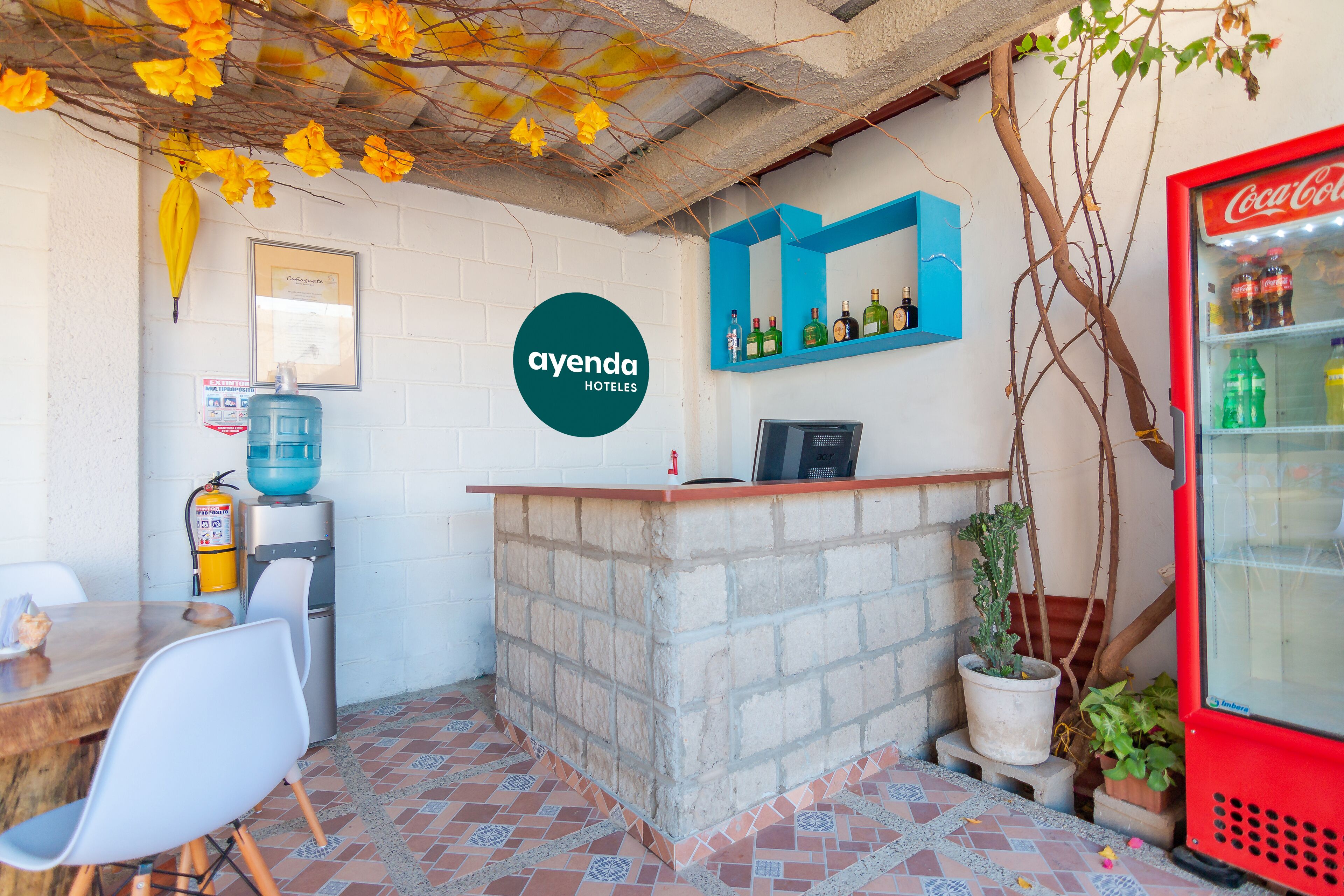 Un espace d’accueil comprenant un réfrigérateur à boissons Coca-Cola, un distributeur d’eau et un coin salon avec des chaises et une table.