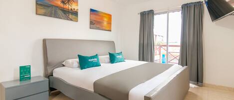 A modern bedroom with a bed, nightstands, a flat-screen TV, and artwork on the walls.