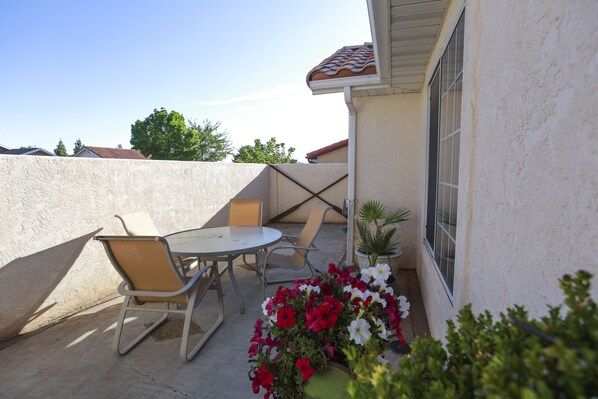 An outdoor patio with a table and chairs, a potted plant, and a flower arrangement.