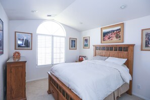 A bedroom with a large bed, a wooden cabinet, and a window with blinds.