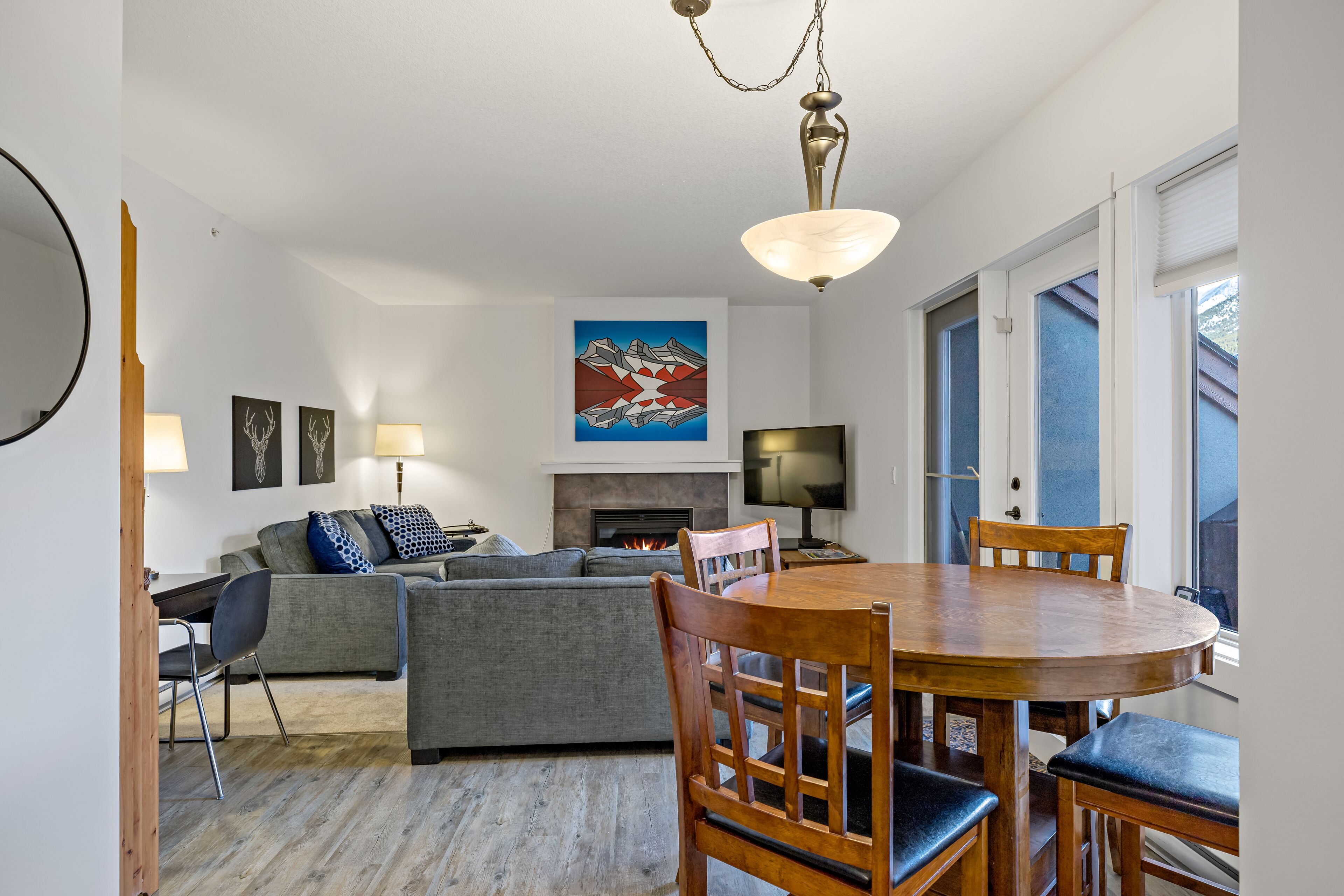 A modern living room with a fireplace, a dining table with chairs, and a sofa.