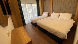 Une chambre d’hôtel avec deux lits, un bureau en bois et une grande fenêtre avec des rideaux.