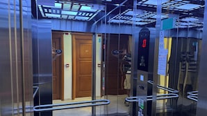 L’intérieur d’un ascenseur est doté d’un écran numérique, de barres d’appui et d’une porte en bois.