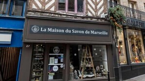 A building with a sign reading "La Maison du Savon de Marseille" at the ground floor.