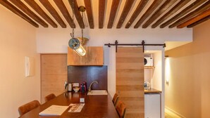 A modern kitchen with wooden cabinetry, a large dining table, and a hanging light fixture.