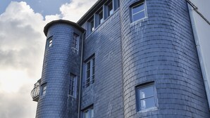 Ein Gebäude mit einer geschwungenen Fassade, zahlreichen Fenstern und einem zylindrischen Turm.