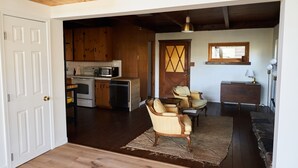 Amplia sala de estar con cocina, piso de madera y un gran ventanal.