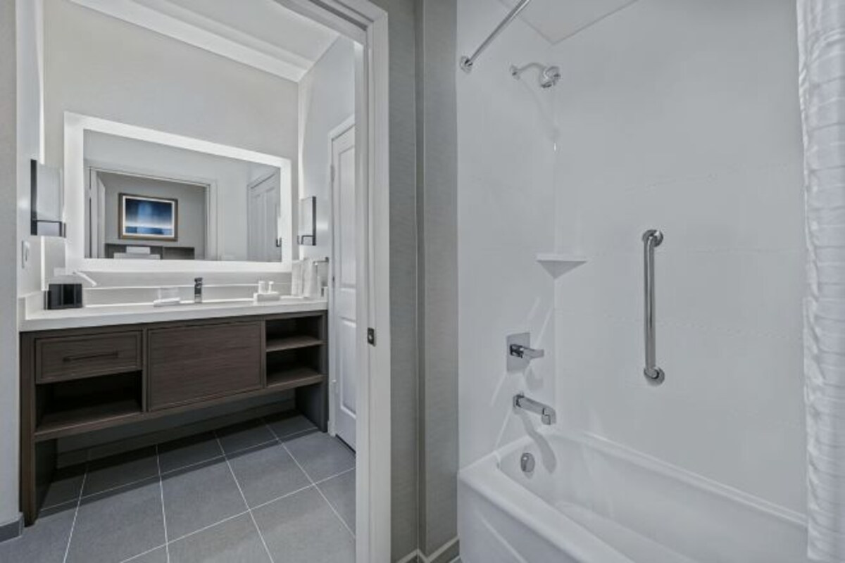 Un baño moderno con un espejo grande, una bañera y una ducha.