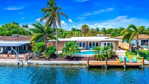 A beachfront property with a swimming pool, palm trees, and a dock. - EXQUISITE HEATED POOL+WATERFRONT! 1 MILE TO BEACH! (Pompano Beach)