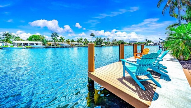 A wooden dock with blue chairs and a poolside area. - EXQUISITE HEATED POOL+WATERFRONT! 1 MILE TO BEACH! (Pompano Beach)