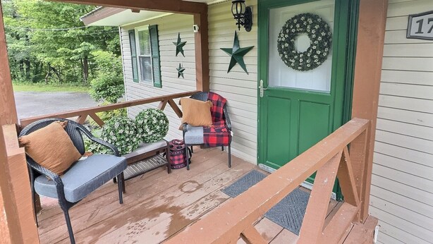 A covered porch with a bench, a door with a wreath, and a star decoration. - The Perfect Private Escape (Lorraine)
