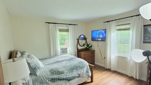 A bedroom with a bed, dresser, TV, and windows. - The Perfect Private Escape (Lorraine)