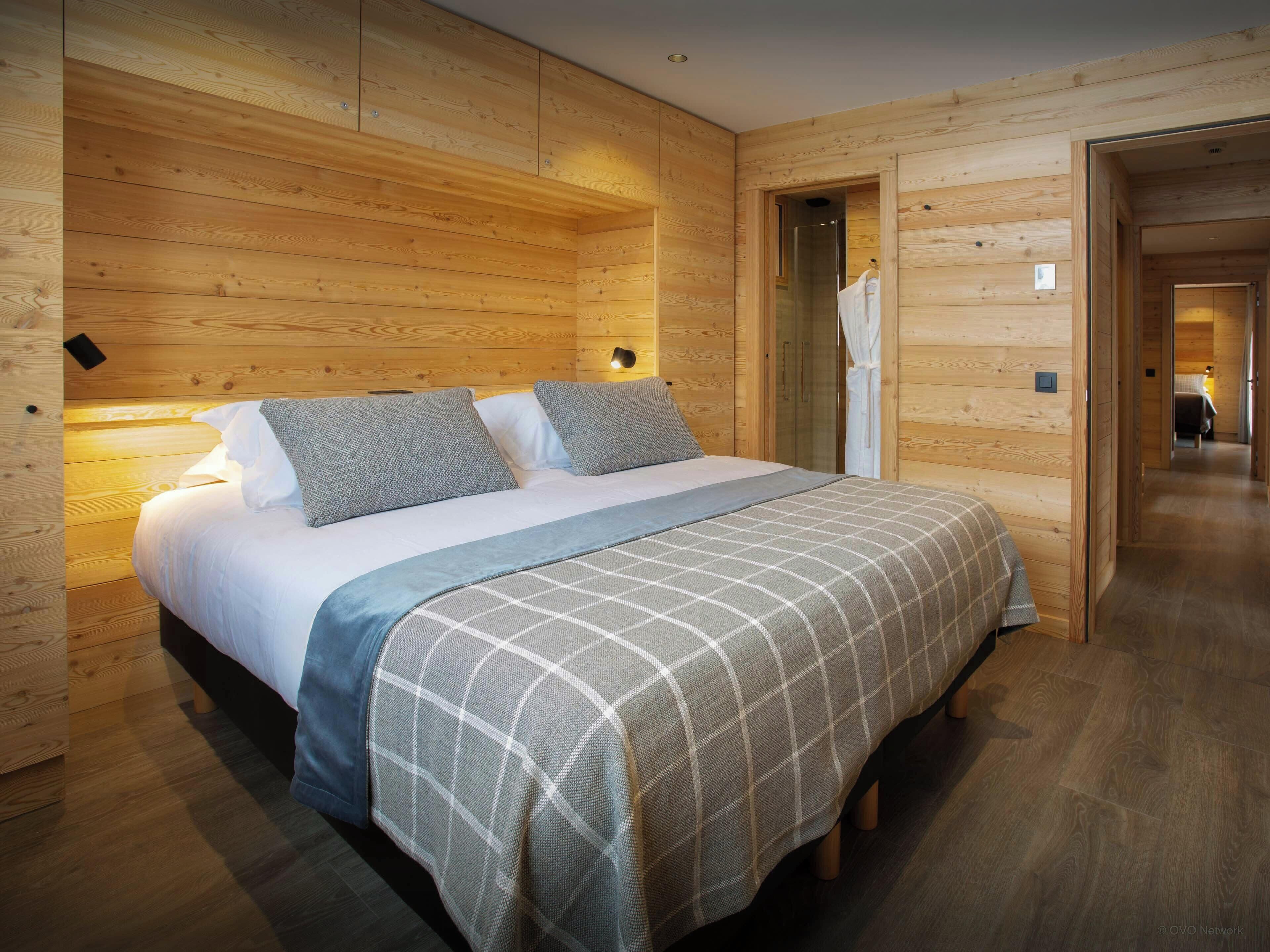 A wooden-paneled room with a bed, a nightstand, and a walk-in closet.